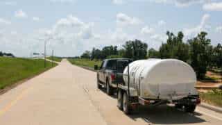 Truck Hauling 1600 D.O.T. Water Trailer On A Road