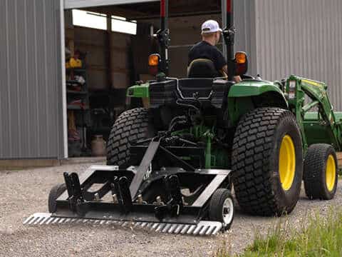 A man riding a tractor with a TR3 attached to it.