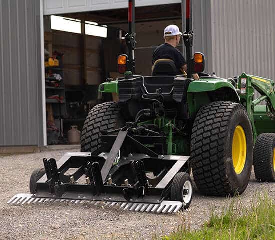 A man riding a tractor with a TR3 attached to it.