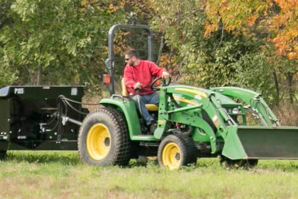 An operator controlling a PTO manure spreader from the tractor seat.